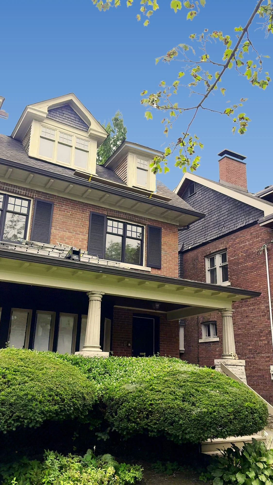 The house from the side, with dark shutters and sashes against the brick
