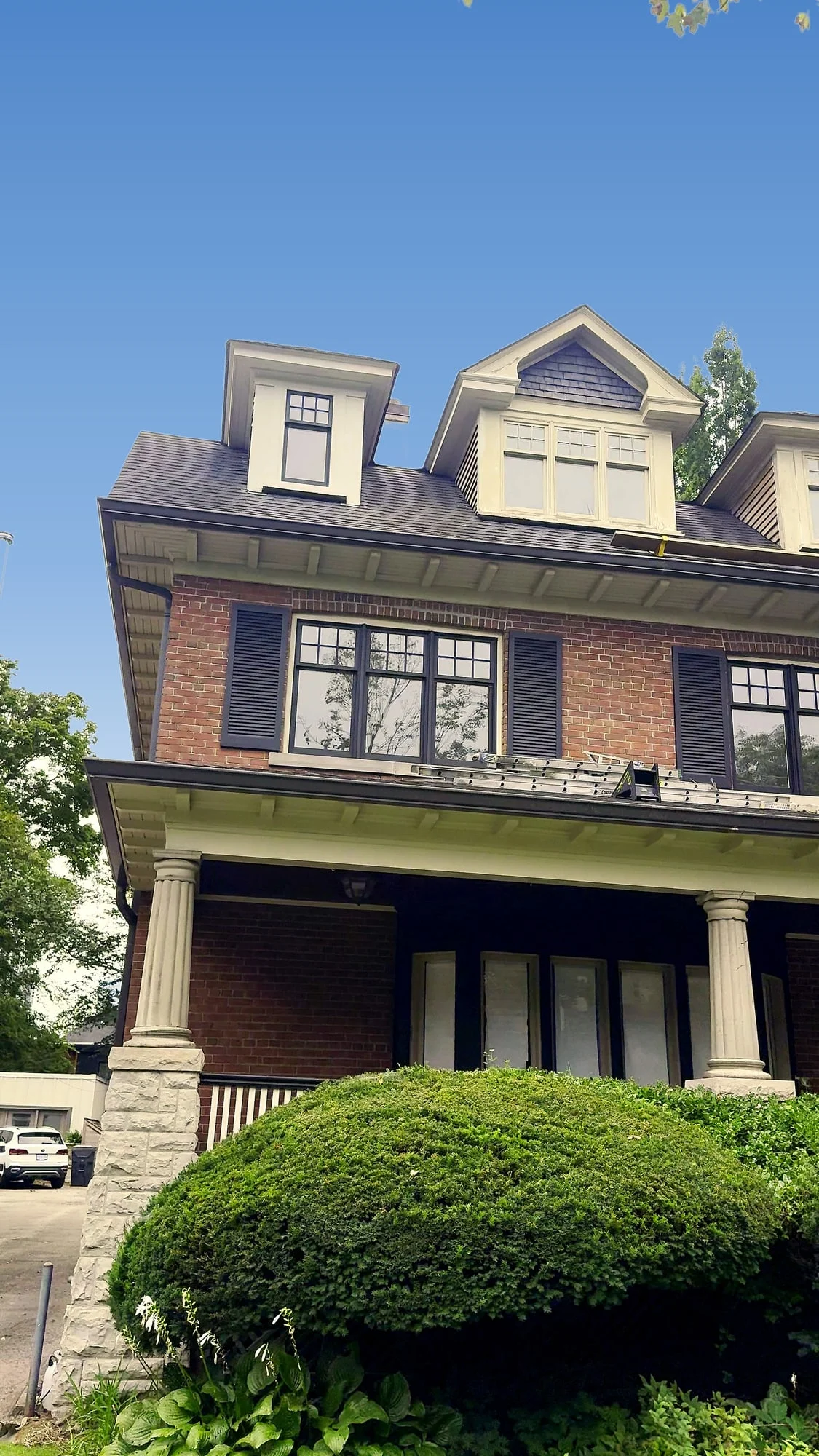 Brick house with dark Iron Mountain shutters and window sashes after the exterior repaint