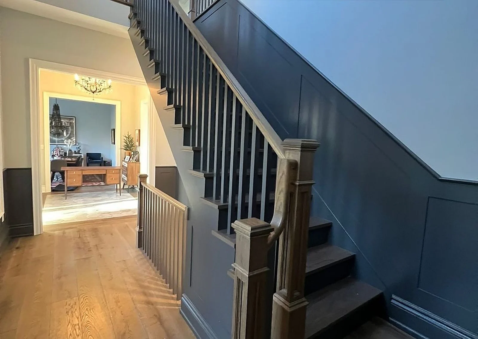 Staircase with navy wainscoting and dark treads