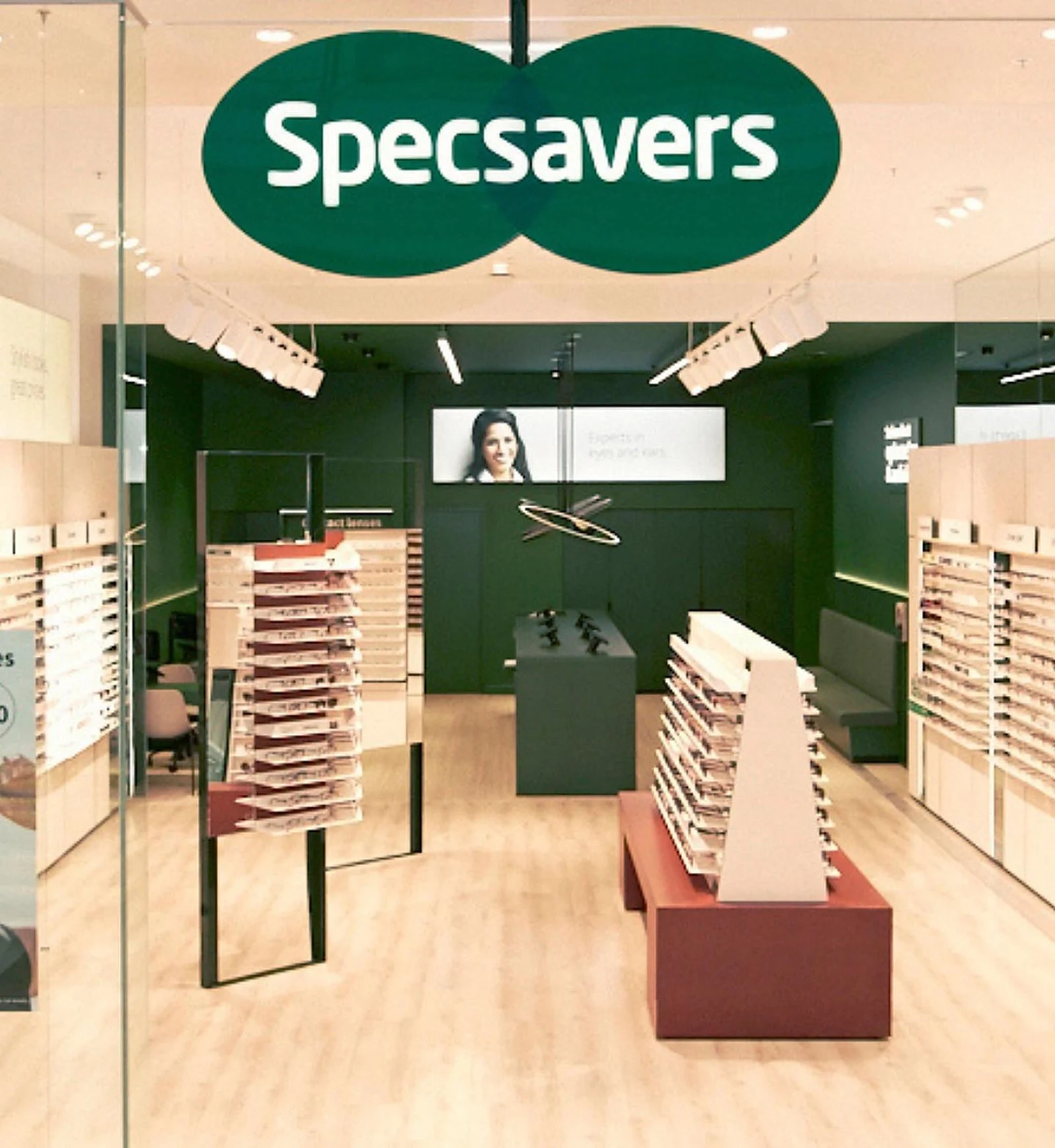 Specsavers store interior, green feature wall with logo