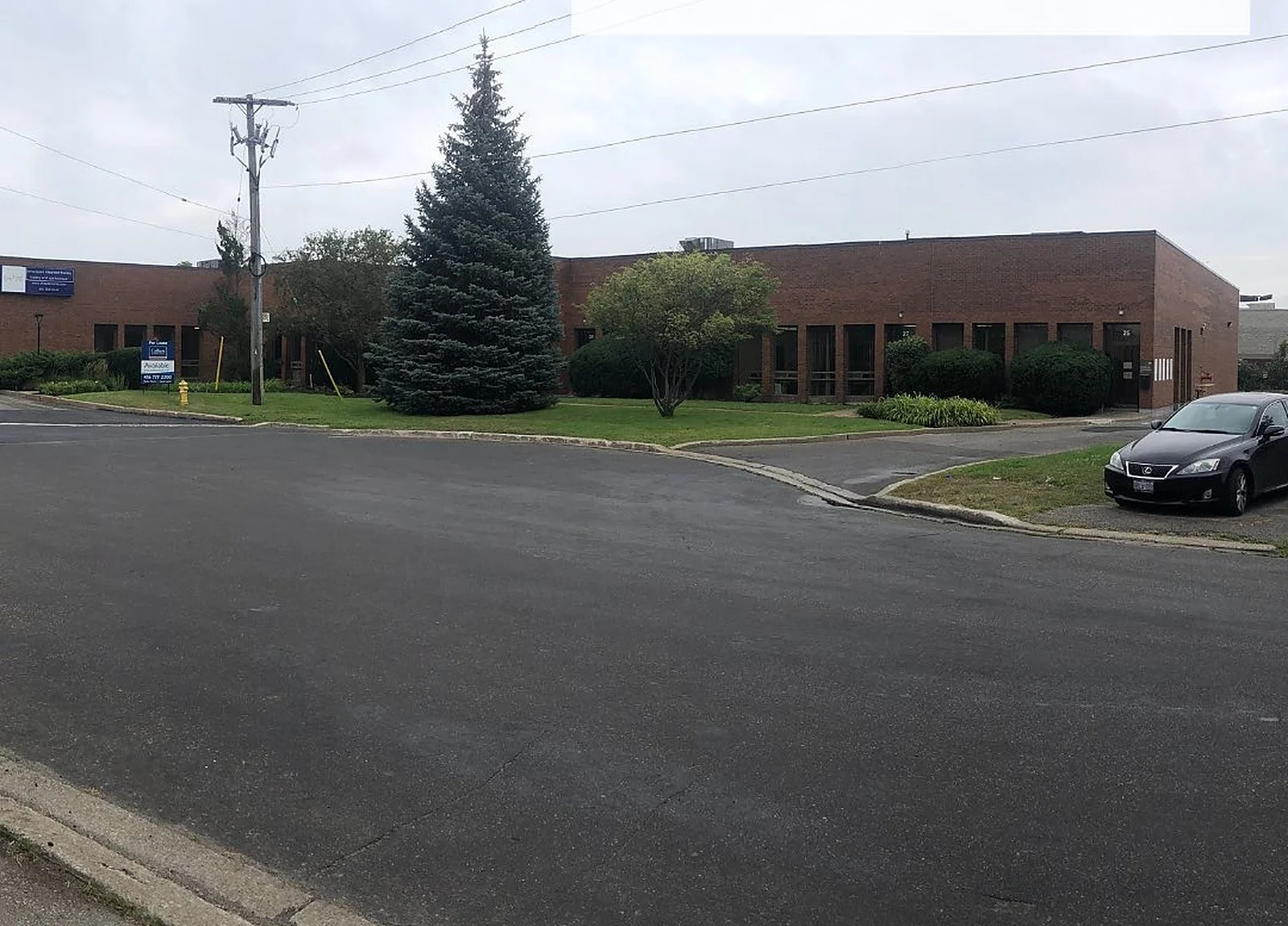 BEFORE: brown brick industrial building with pine tree