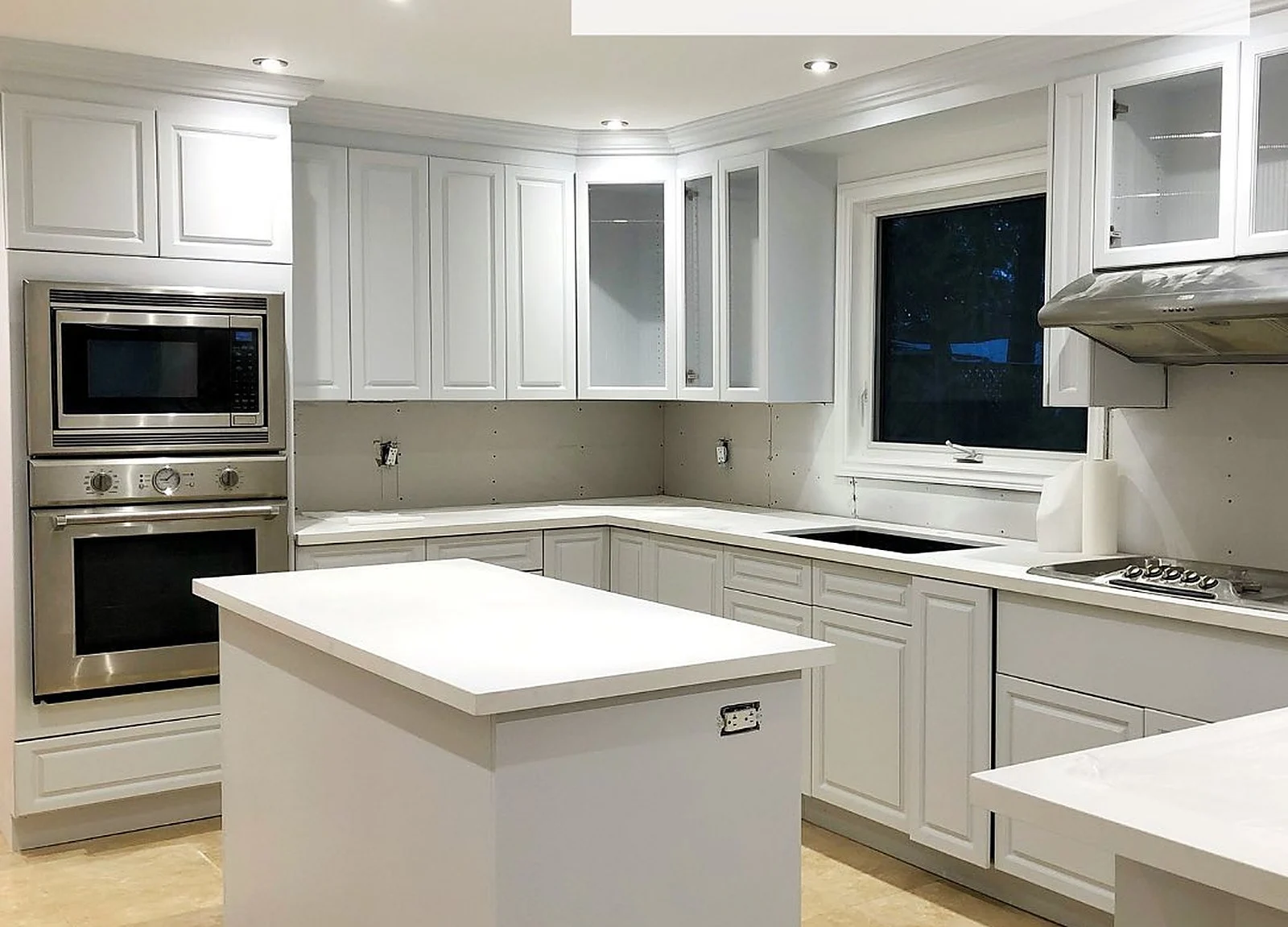AFTER: same kitchen cabinets painted light grey, white counters