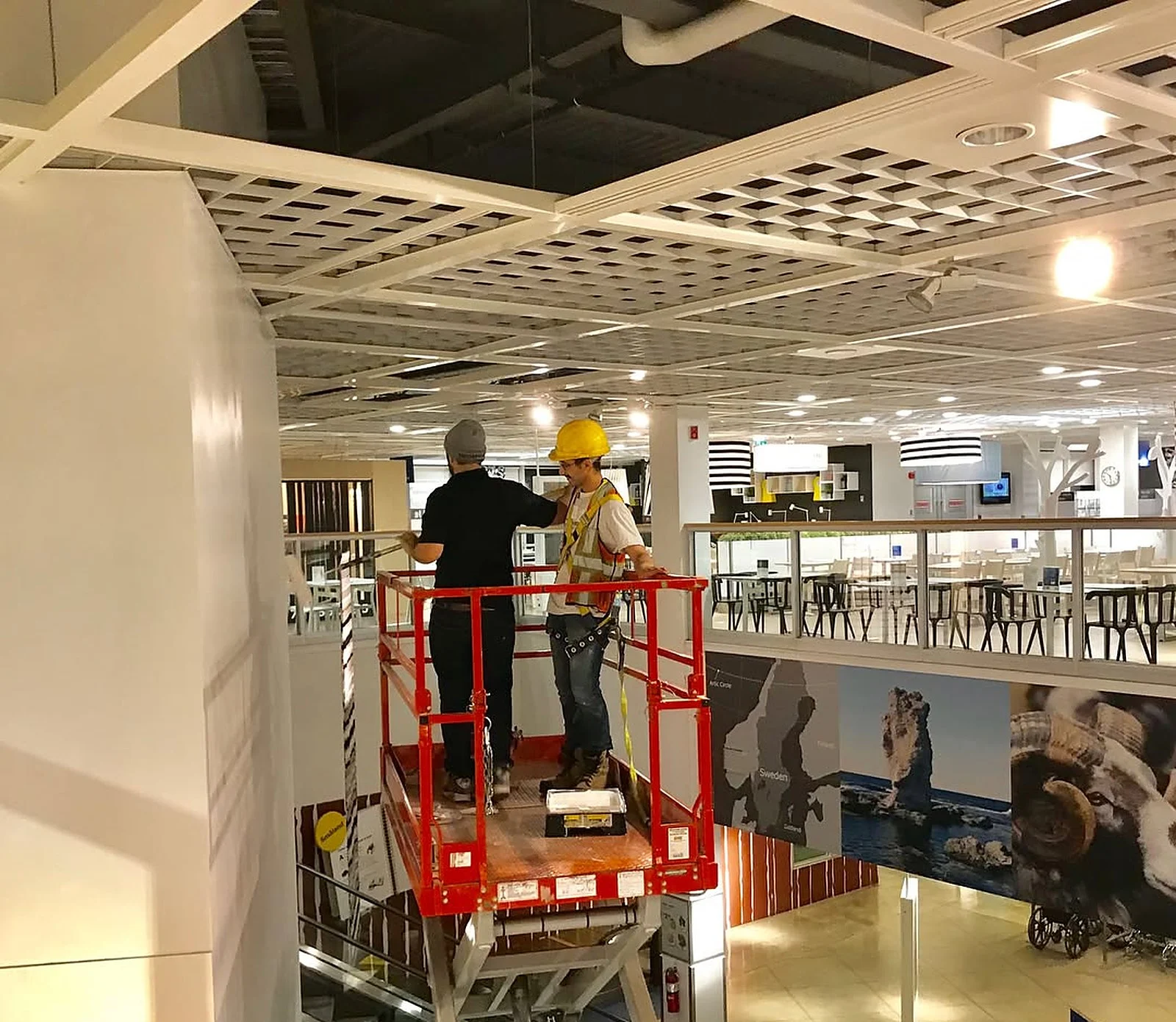 Crew on red scissor lift painting/removing wall coverings inside IKEA Vaughan