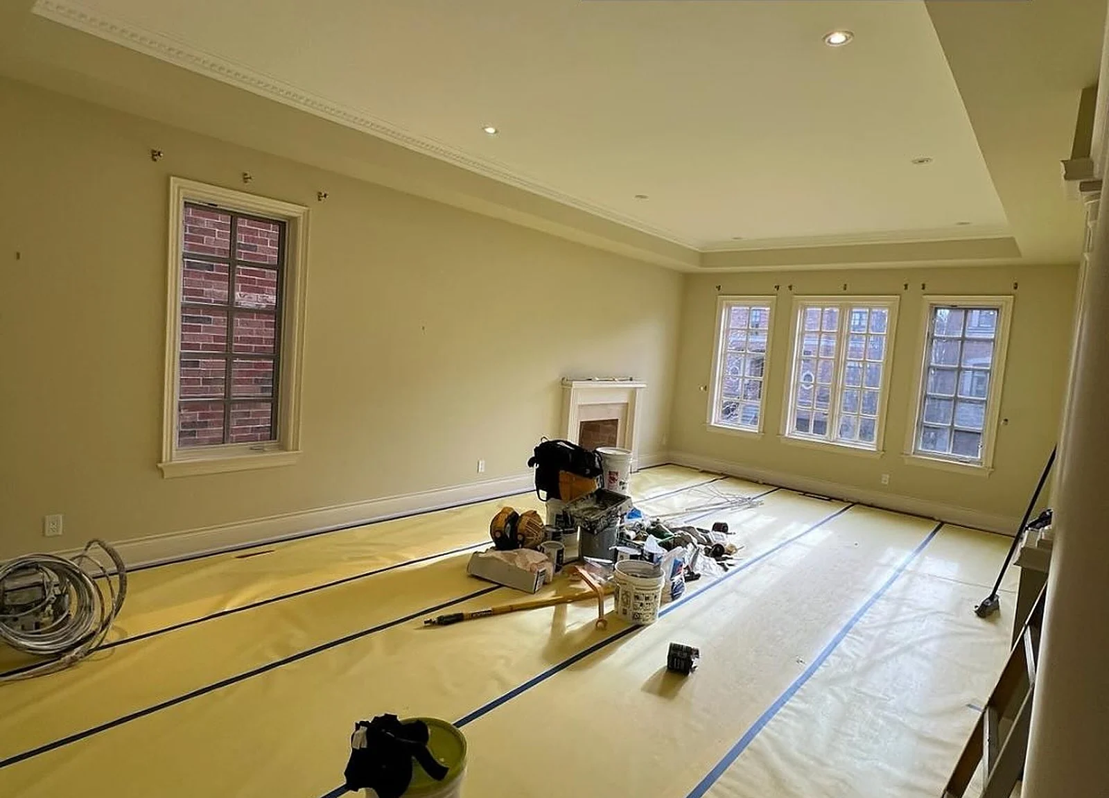BEFORE: living room olive-green walls, floor paper, tools
