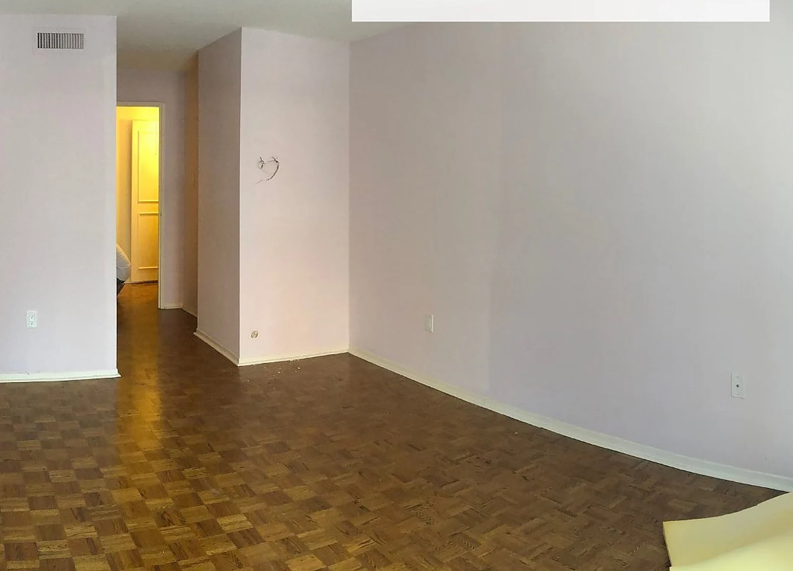 BEFORE: empty condo room, parquet floor, patched walls