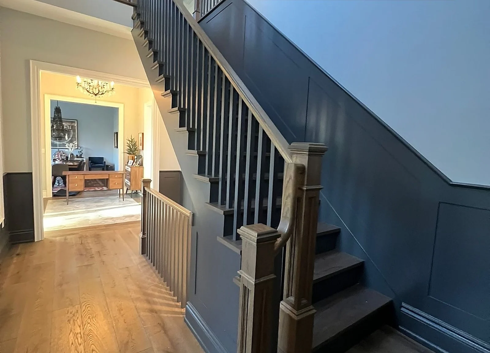 AFTER: staircase with dark navy/charcoal lower wainscoting and black spindles, classic look