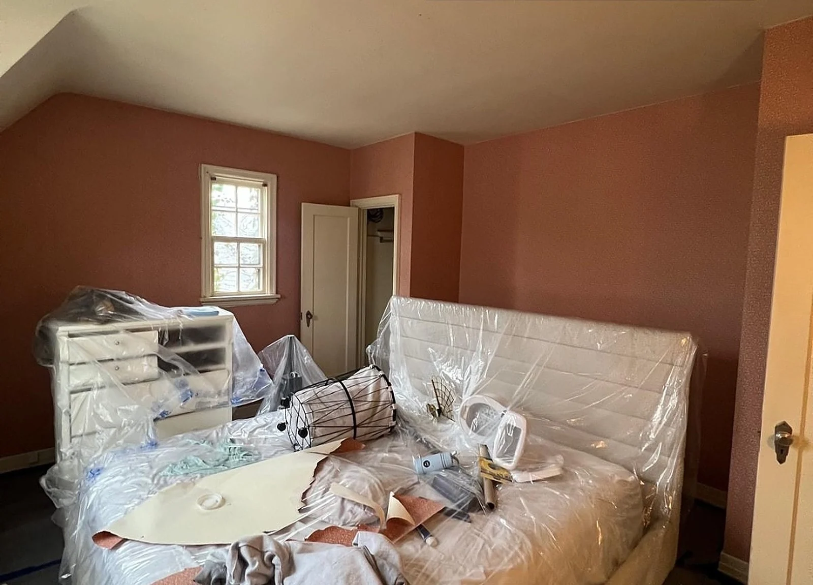 BEFORE: bedroom with terracotta walls, furniture under plastic