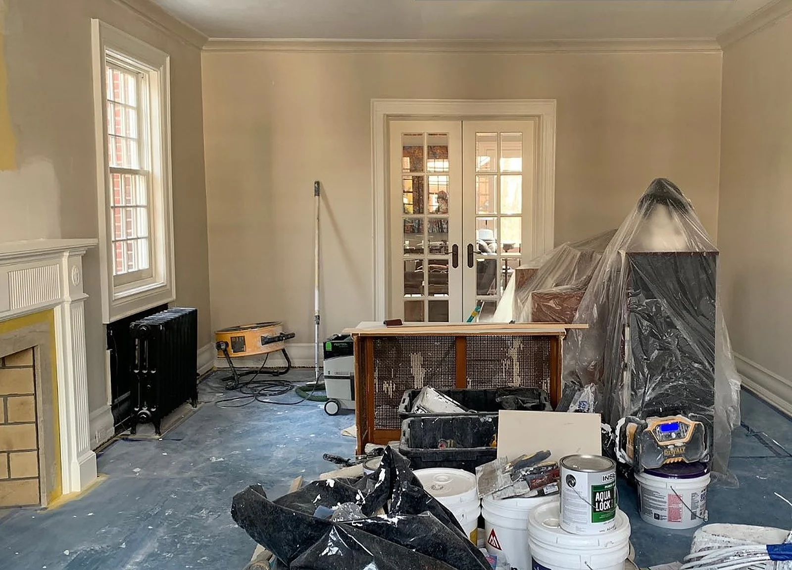BEFORE: living room mid-job, debris and paint buckets