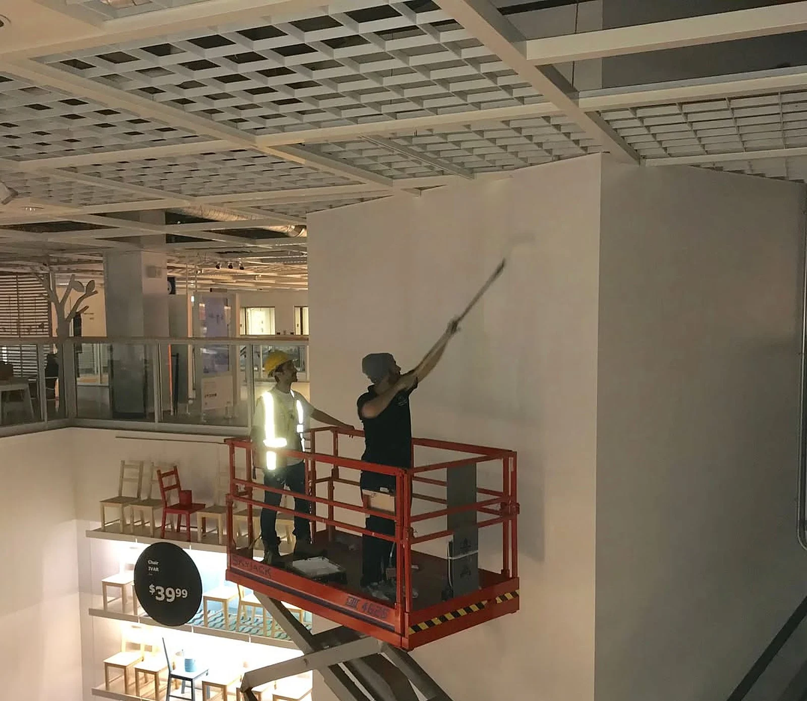 Painter on scissor lift rolling wall inside IKEA