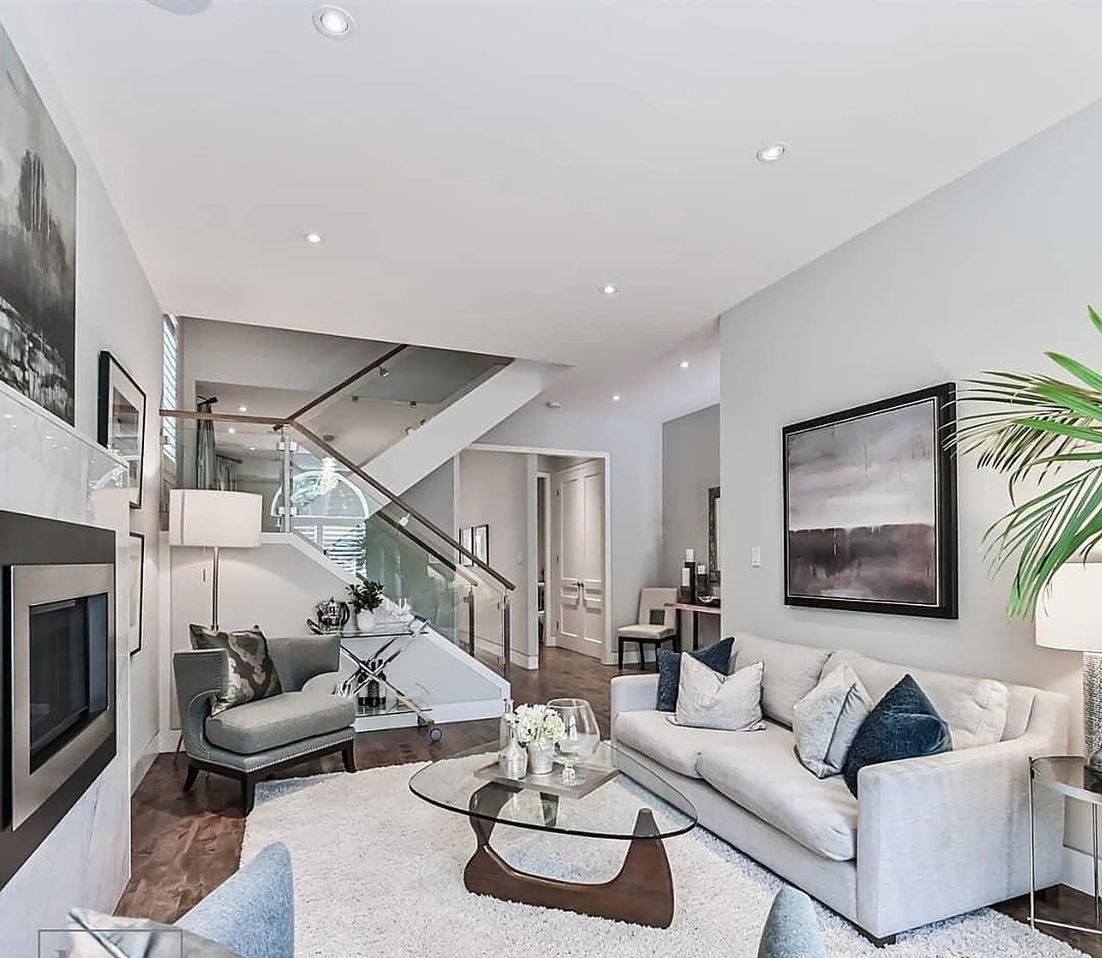 Open living room with glass staircase, white walls