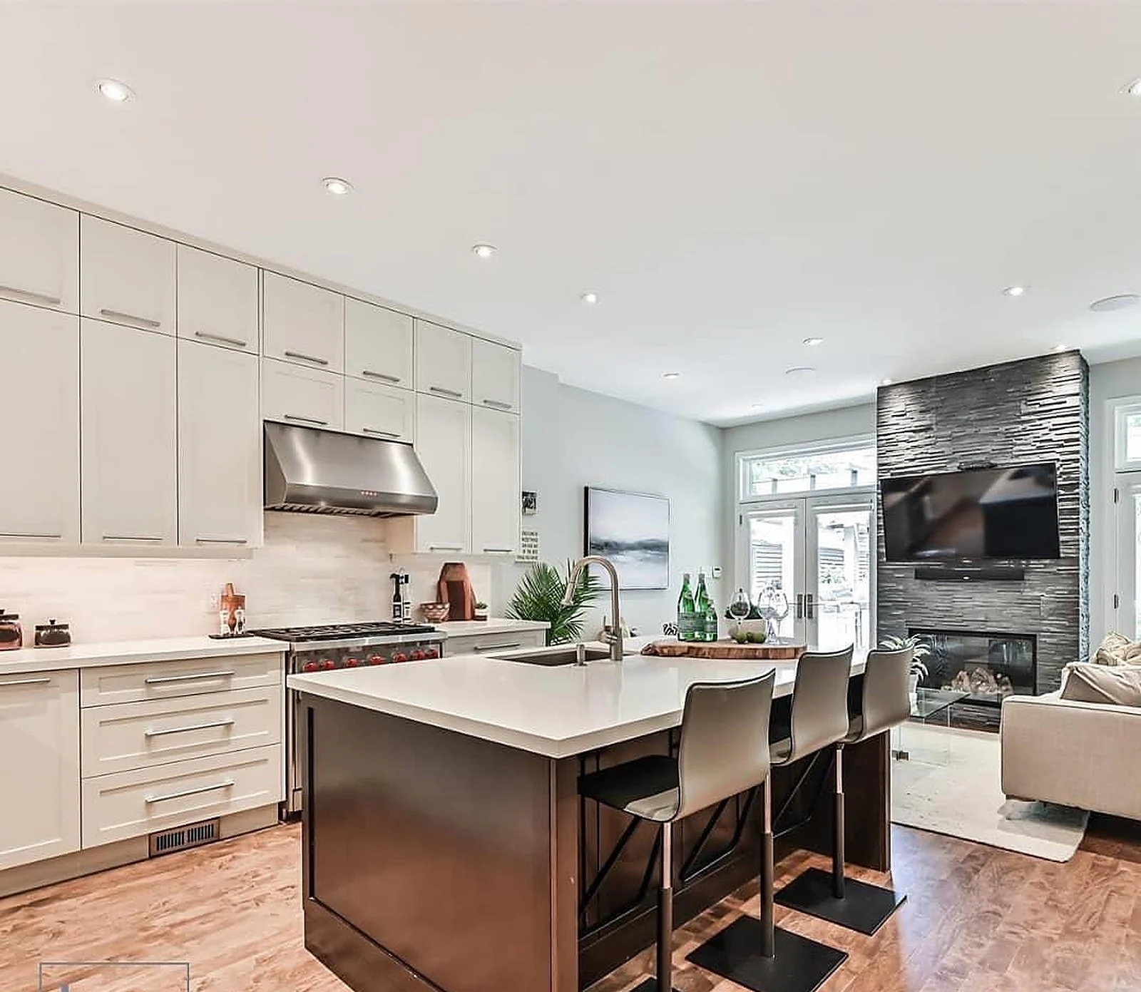 White kitchen with dark island, stone fireplace