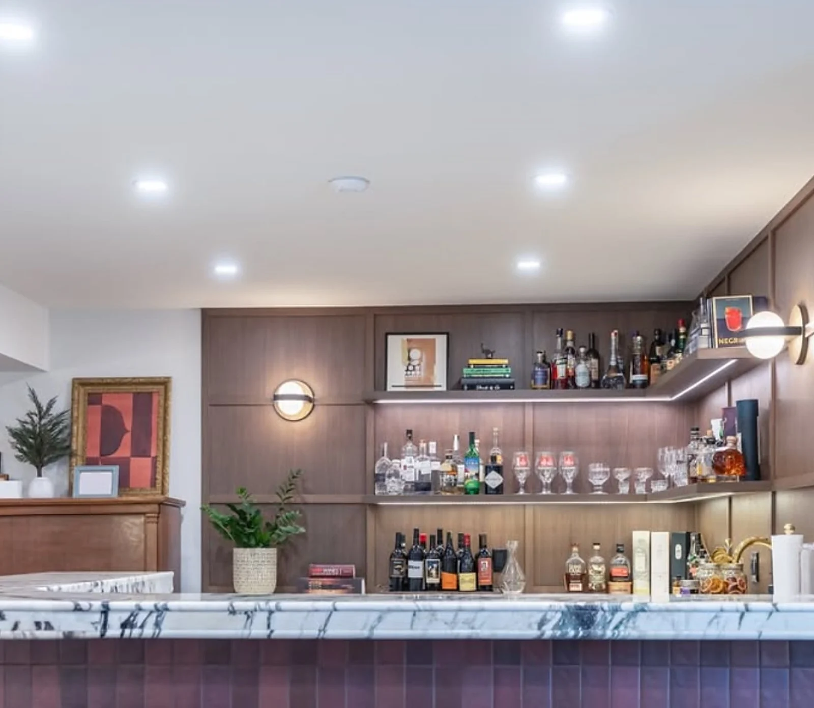 Basement bar with wood shelving, burgundy cabinetry