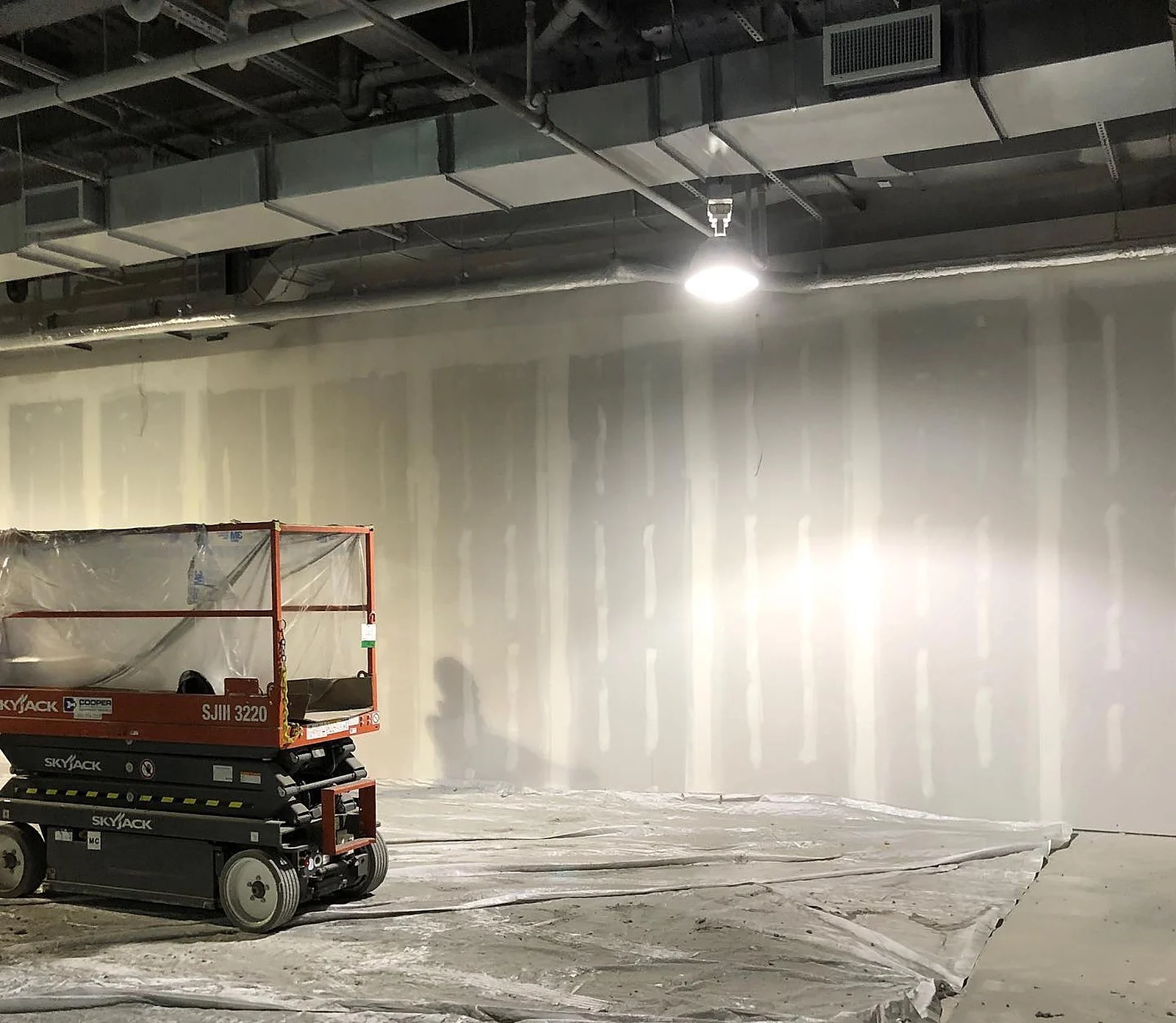 In progress: empty drywalled store with scissor lift