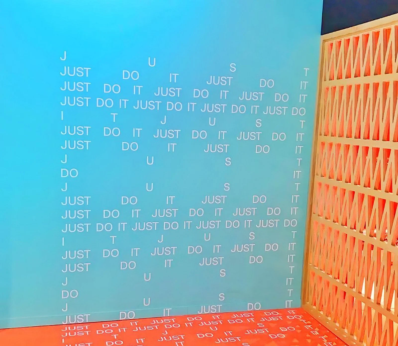Nike teal "Just Do It" text wall with orange lattice