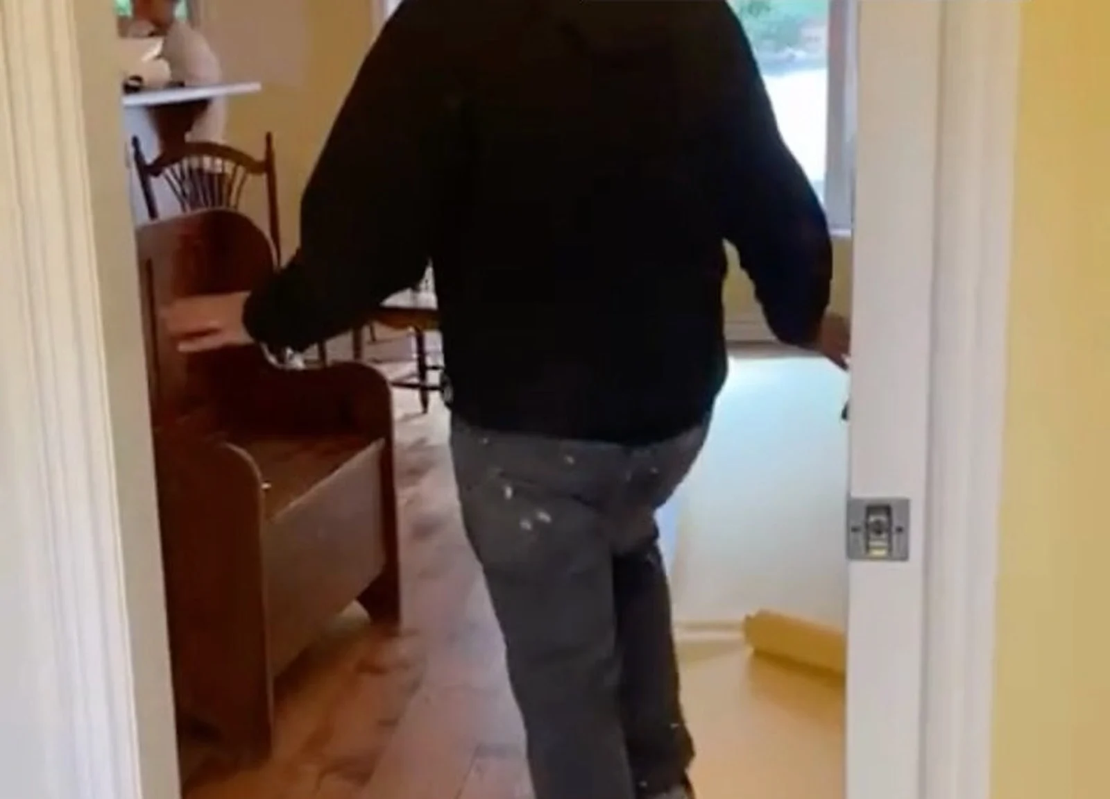 BEFORE: man in hoodie in cottage doorway (video still)