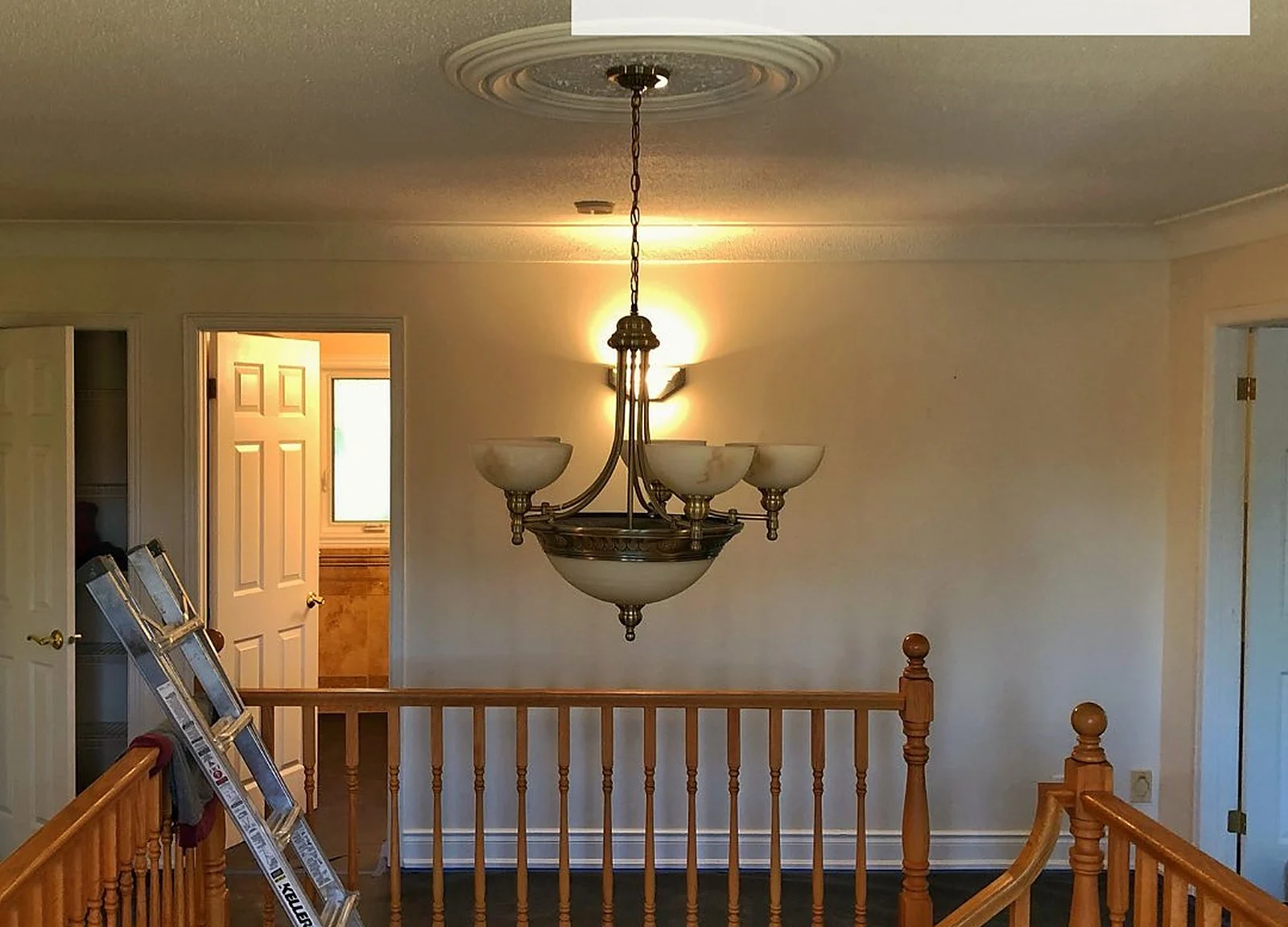 BEFORE: upper hallway, orange oak railing, chandelier