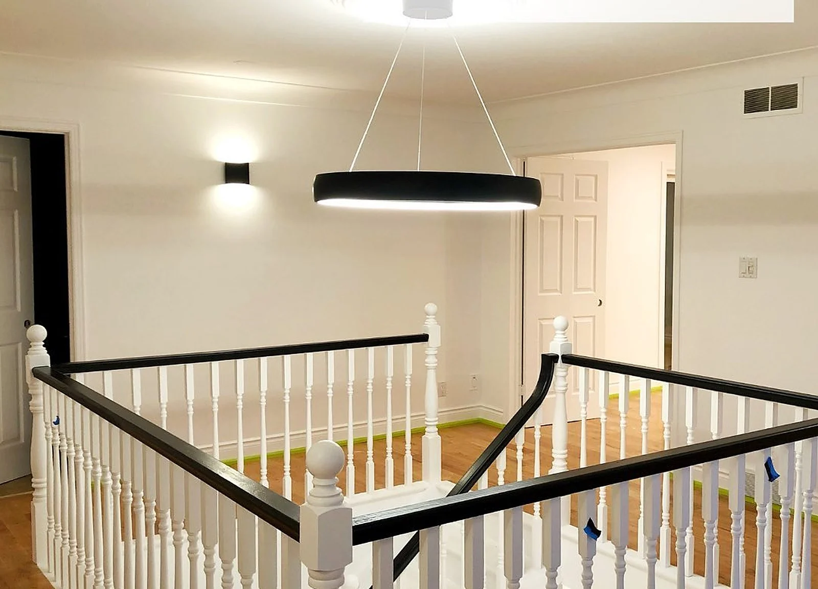 AFTER: bright foyer/staircase with white railing, modern pendant