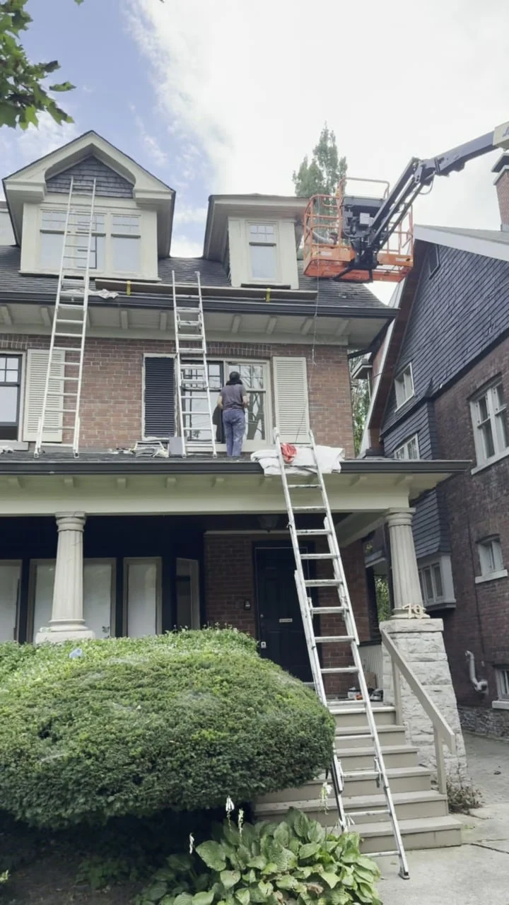 Painters on ladders painting the second-floor shutters and window sashes